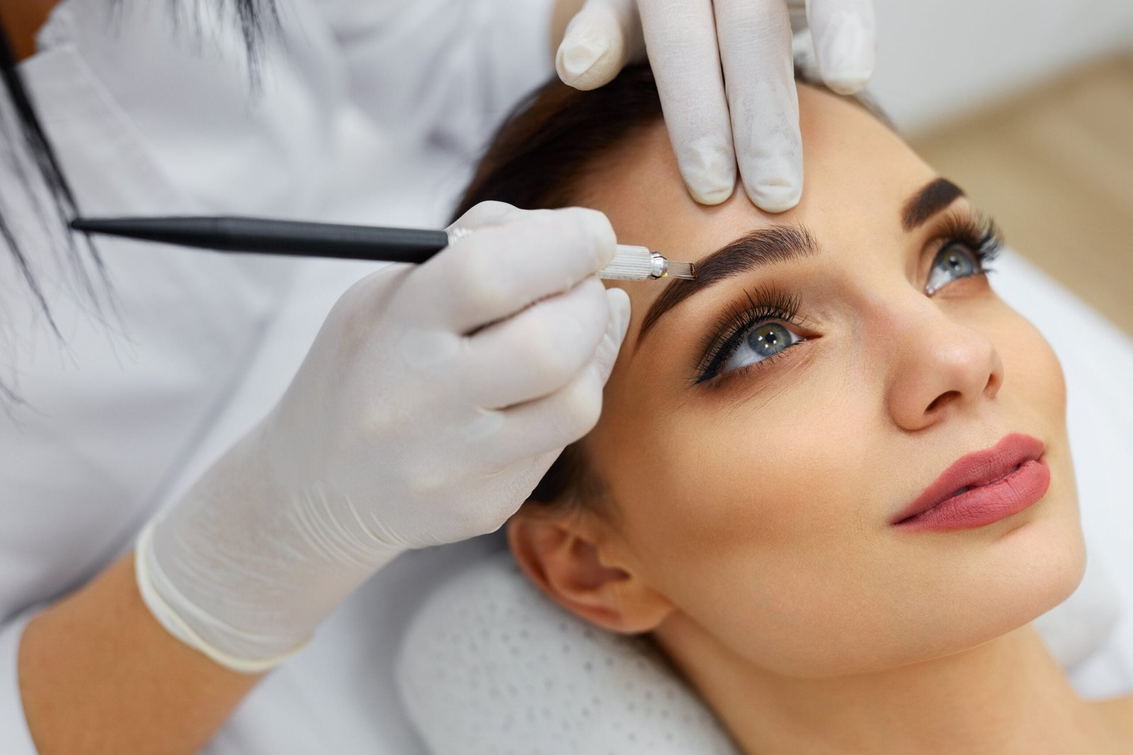 Beautician Doing Eyebrow Makeup Tattoo On Woman Using Machine Beautician Doing Eyebrow Makeup Tattoo On Woman Using Machine